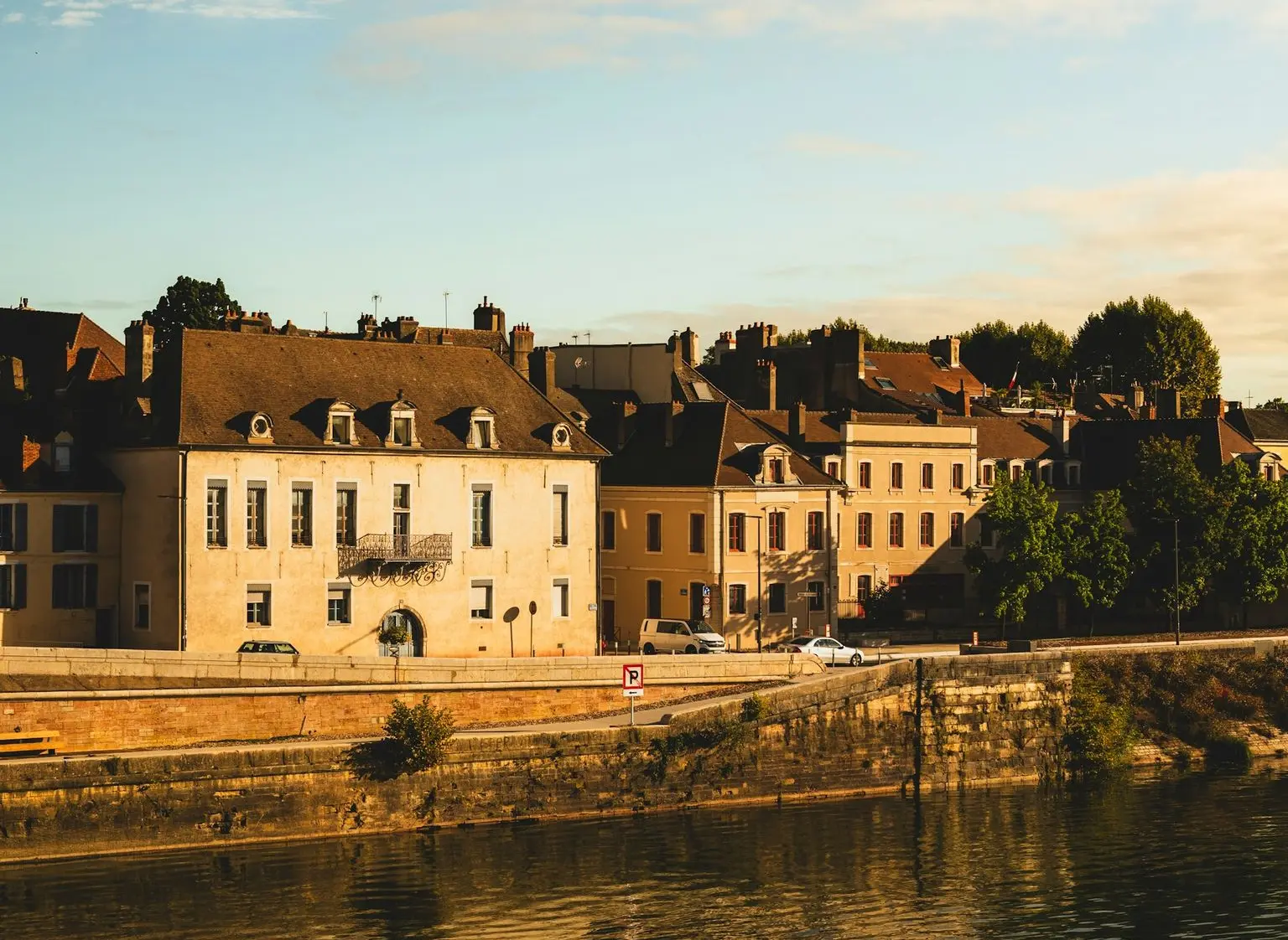 Historic buildings line a river under a cloudy sky