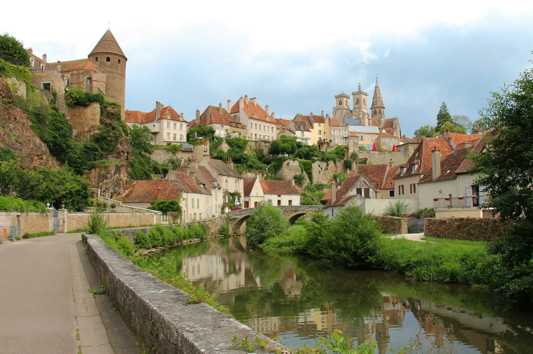 a river running through a village next to a lush green hillside